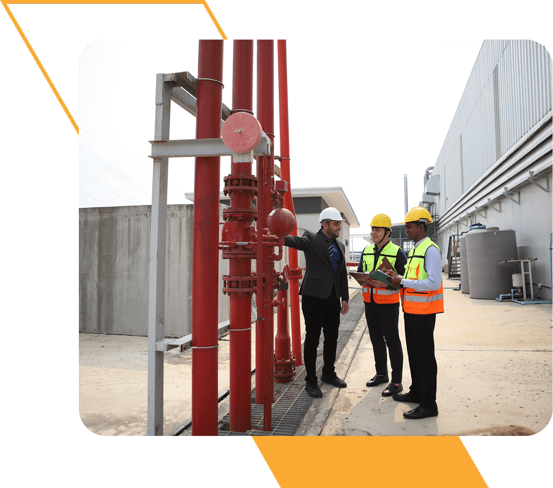 Three workers inspecting industrial pipes outdoors.